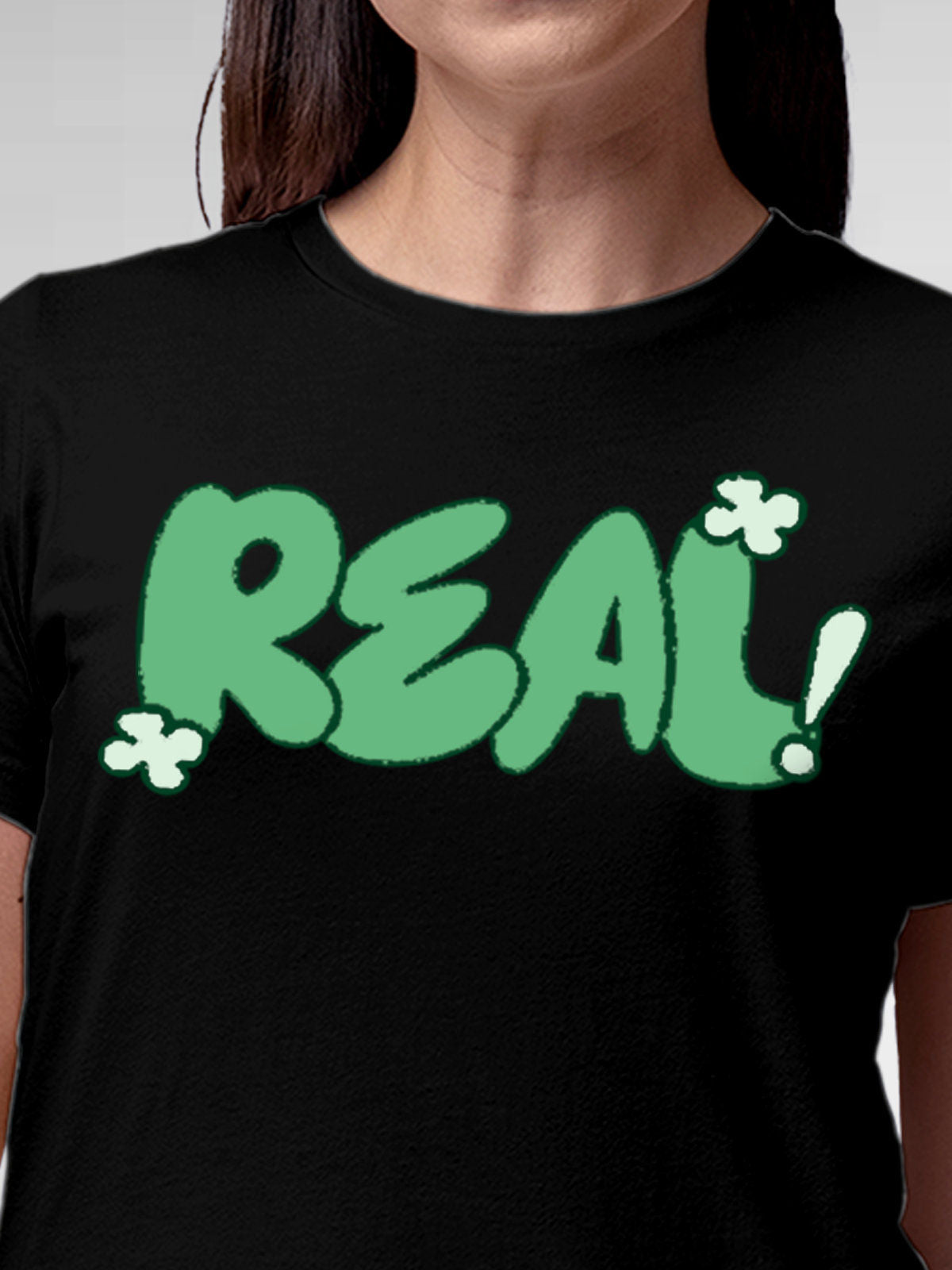 Close up of 'Real' design on Women's Black Round Neck T-shirt, highlighting intricate details and vibrant print.