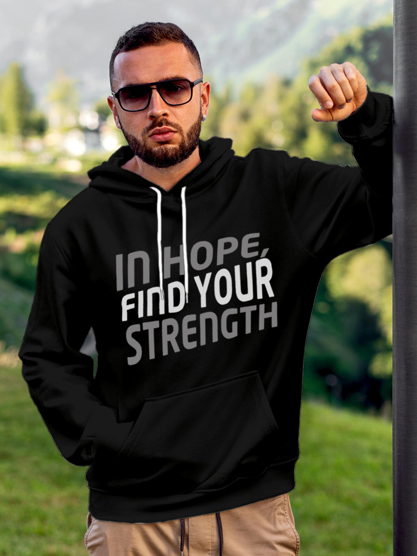 Model wearing Men's Black Hoodie Sweatshirt with 'In Hope, Find Your Strength' design, offering effortless style and premium comfort