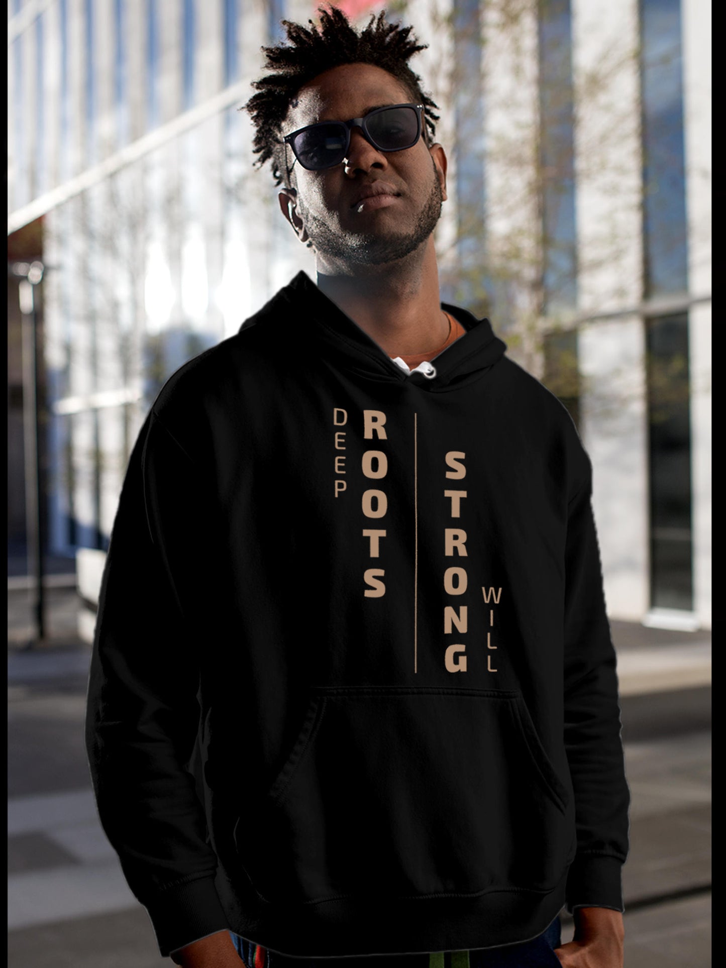 Model wearing Men's Black Hoodie Sweatshirt with 'Deep Roots Strong Will' design, offering effortless style and premium comfort