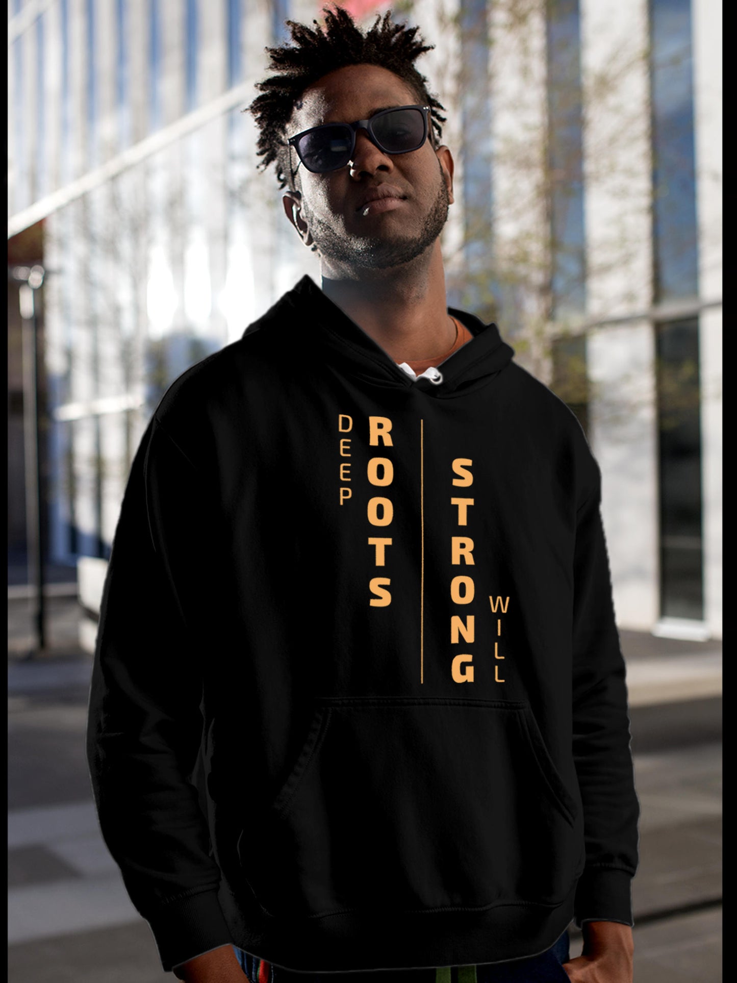 Model wearing Men's Black Hoodie Sweatshirt with 'Deep Roots Strong Will' design, offering effortless style and premium comfort