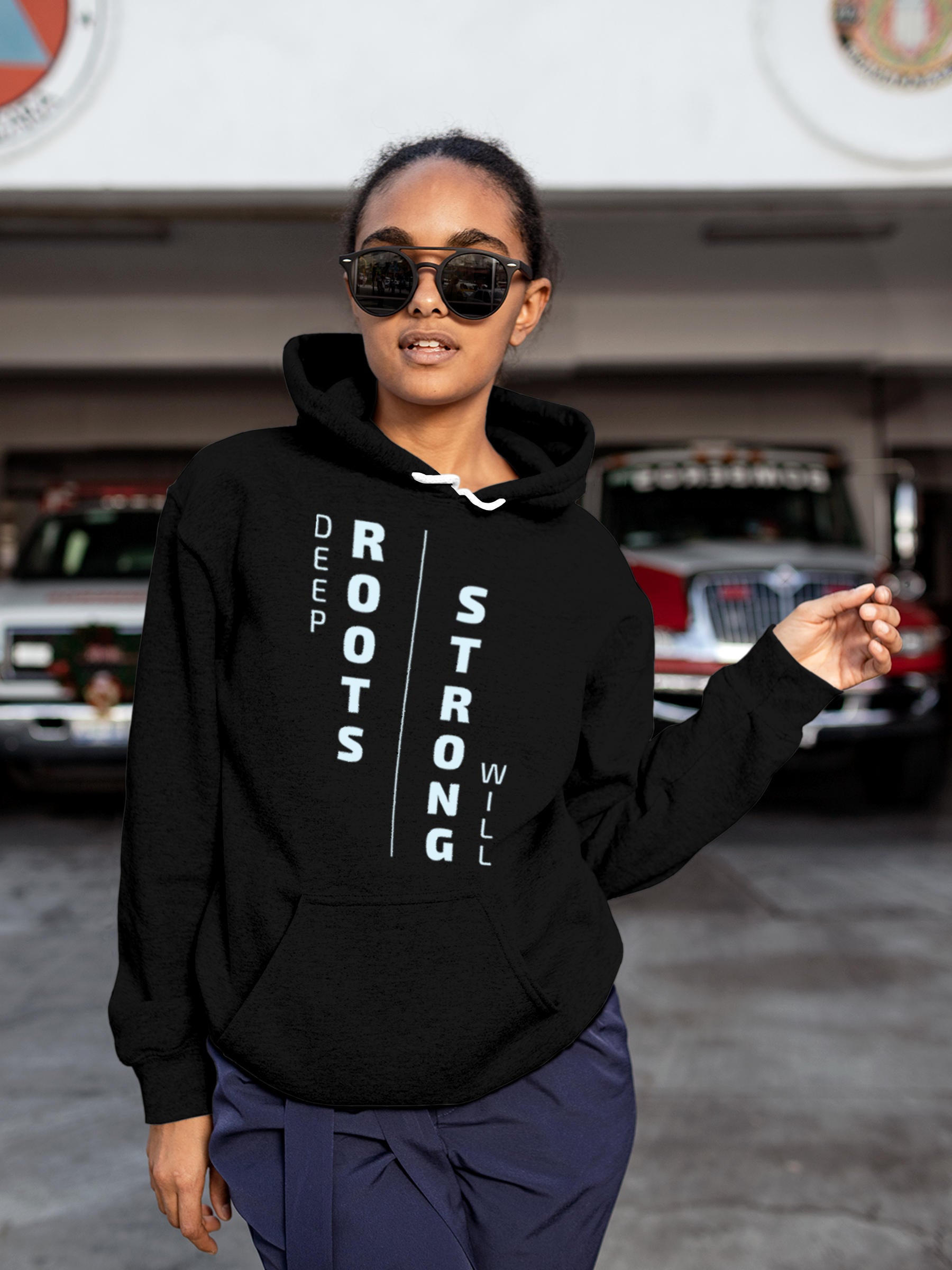 Model wearing Women's Black Hoodie Sweatshirt with 'Deep Roots Strong Will' design, offering effortless style and premium comfort