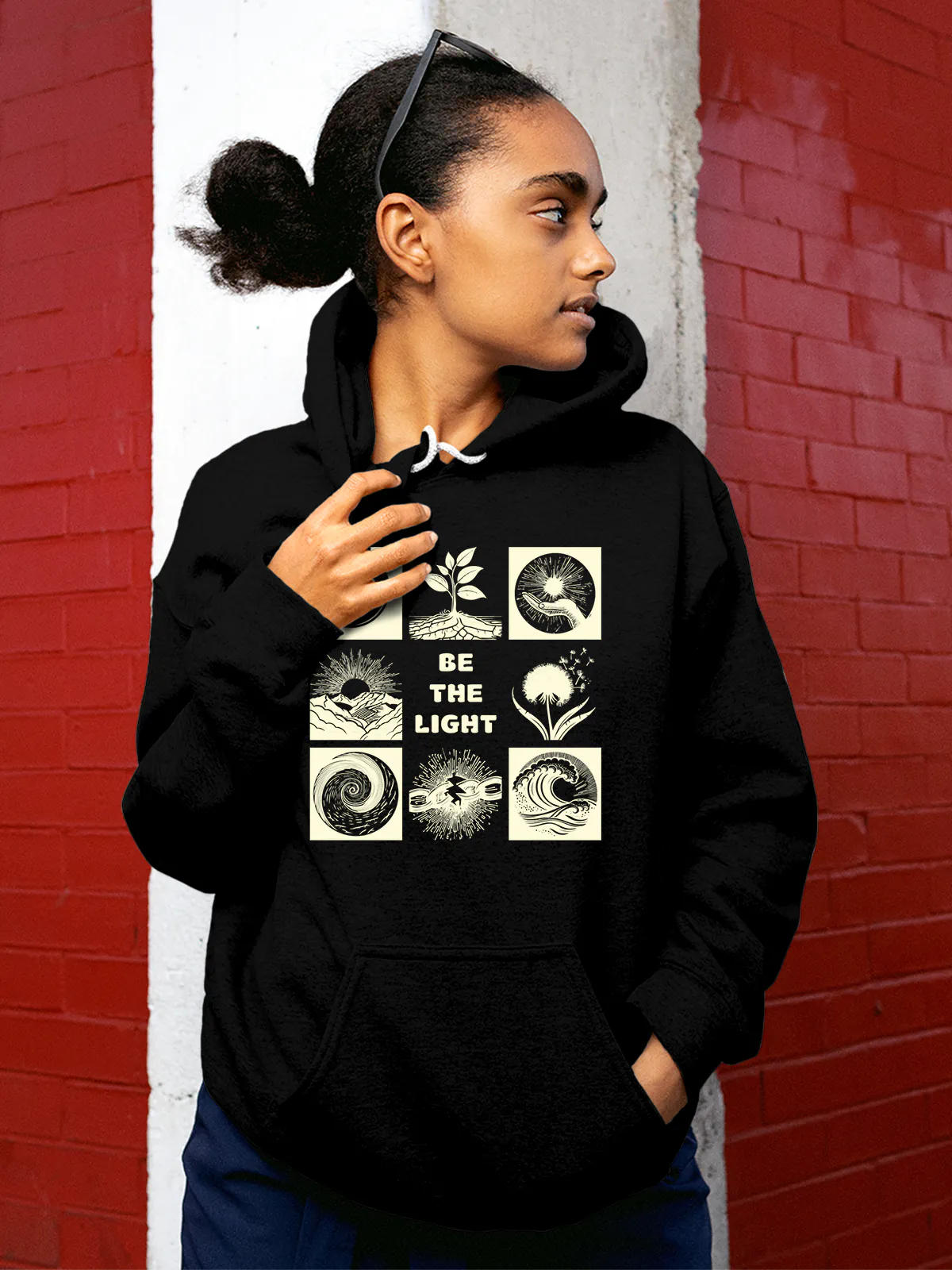 Model wearing Women's Black Hoodie Sweatshirt with 'Be The Light' design, offering effortless style and premium comfort
