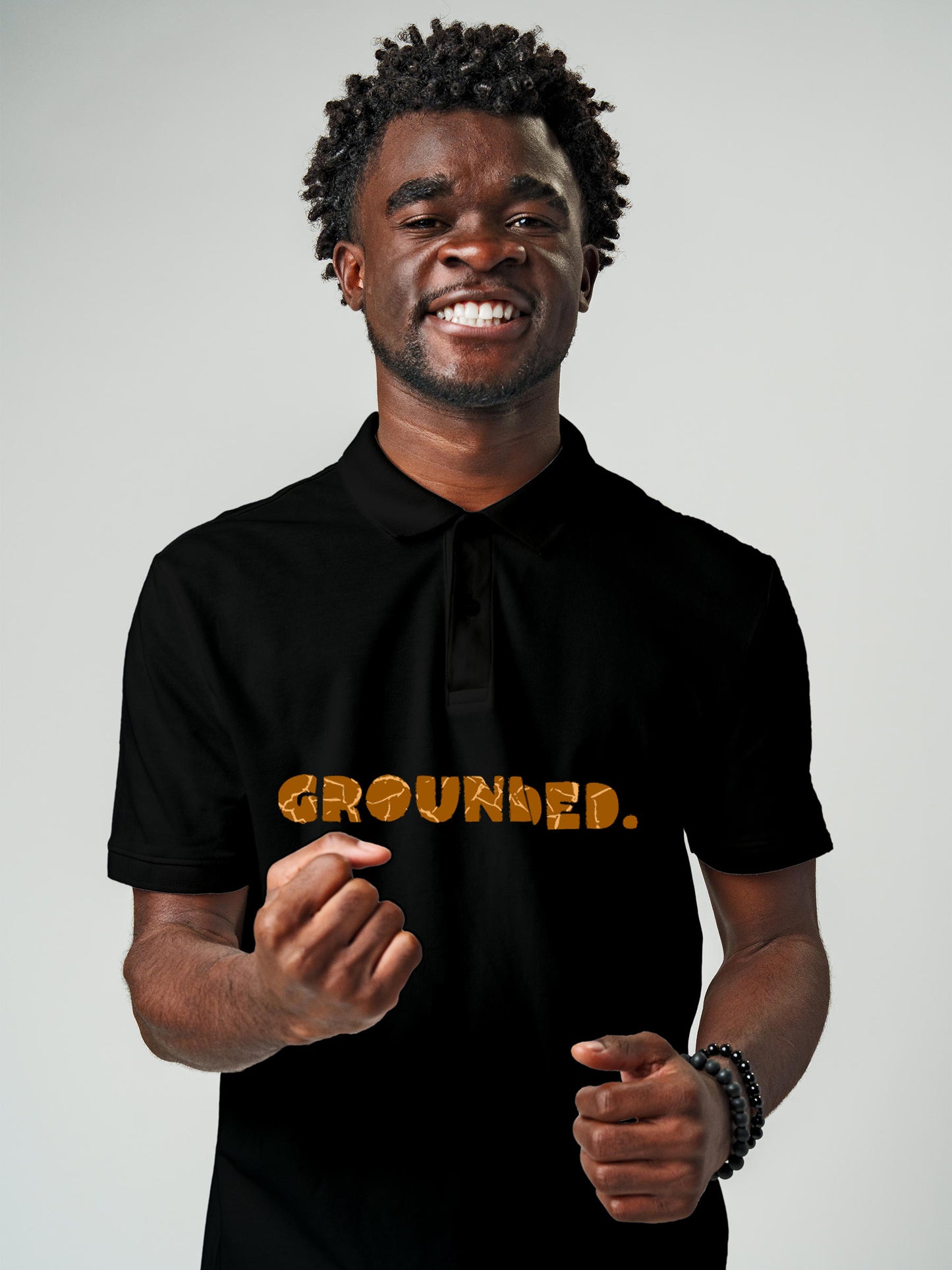 Model wearing Men's Black Polo T-shirt with 'Grounded' design, offering effortless style and premium comfort