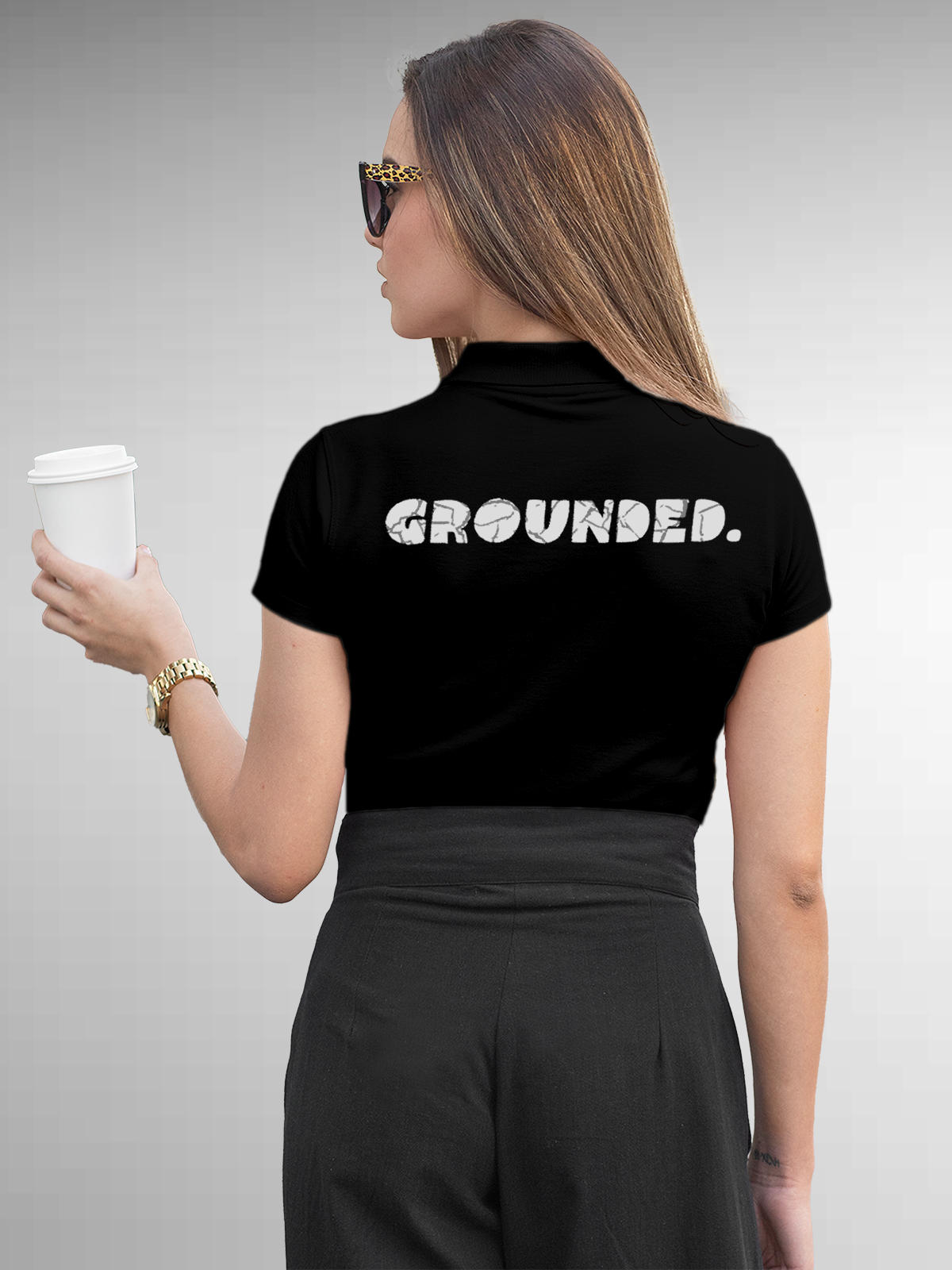 Model wearing Women's Black Polo T-shirt with 'Grounded' design, offering effortless style and premium comfort