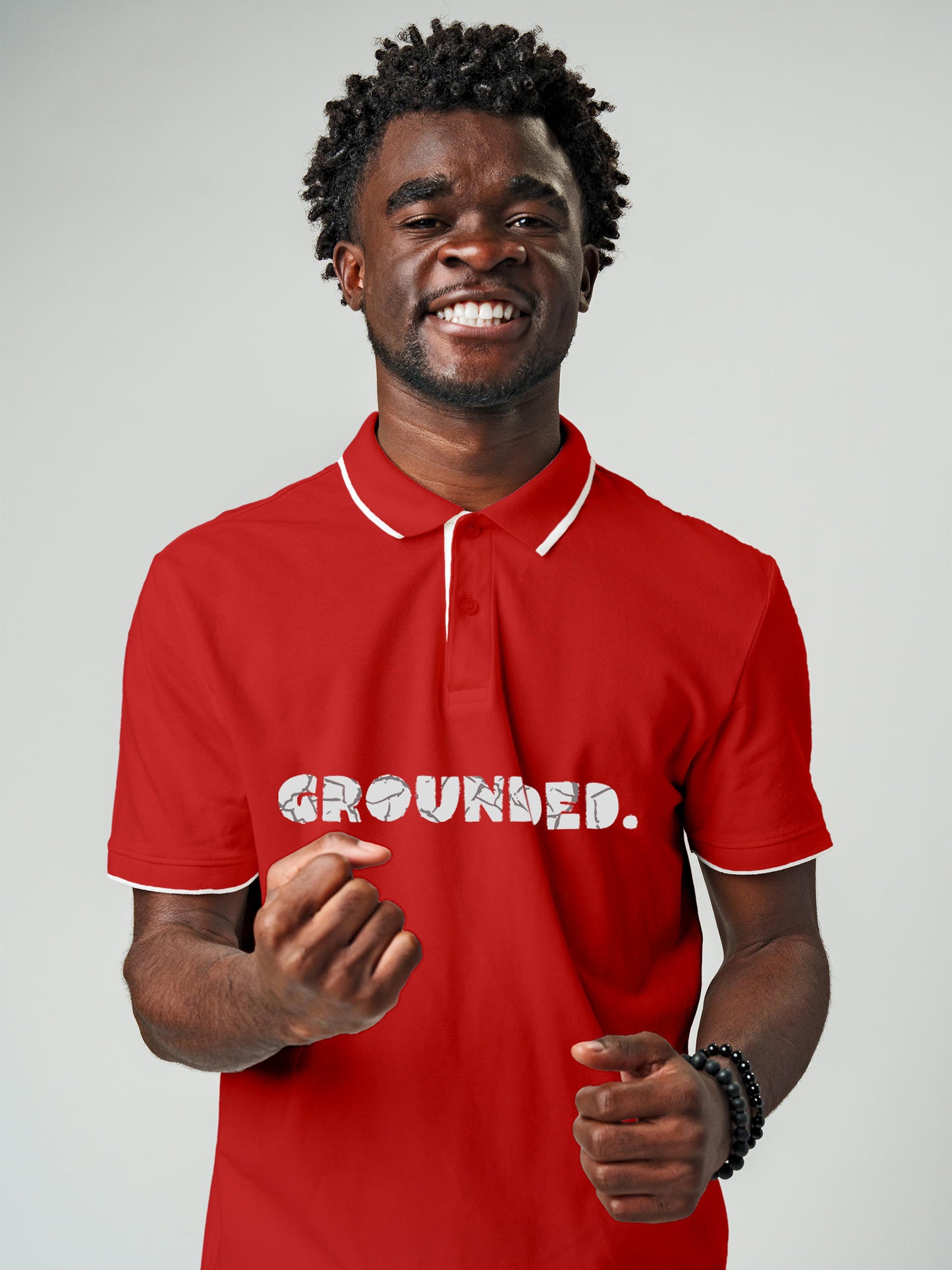 Model wearing Men's Red Polo T-shirt with 'Grounded' design, offering effortless style and premium comfort