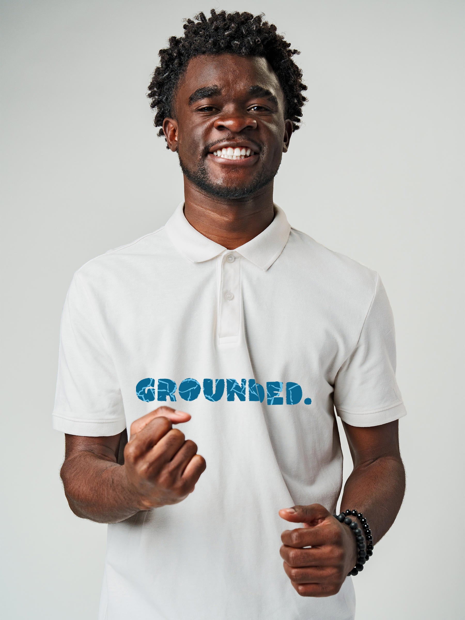 Model wearing Men's White Polo T-shirt with 'Grounded' design, offering effortless style and premium comfort