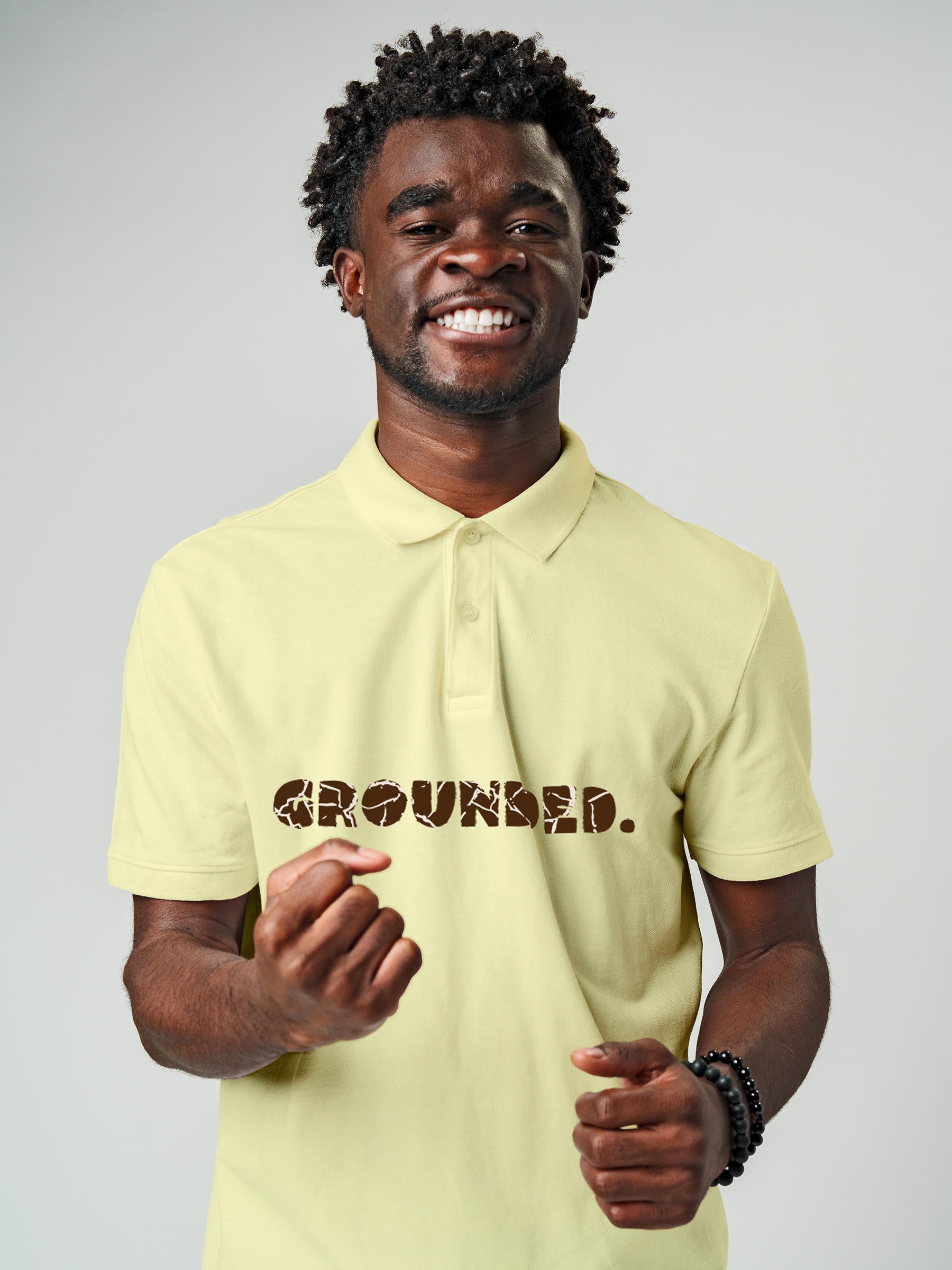 Model wearing Men's Yellow Polo T-shirt with 'Grounded' design, offering effortless style and premium comfort