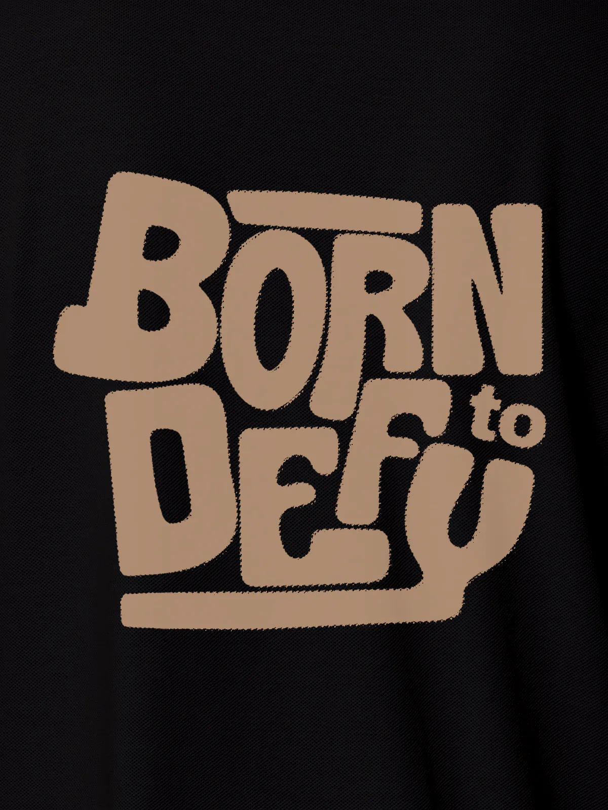 Close up of 'Born To Defy' design on Women's Black Polo T-shirt, highlighting intricate details and vibrant print.