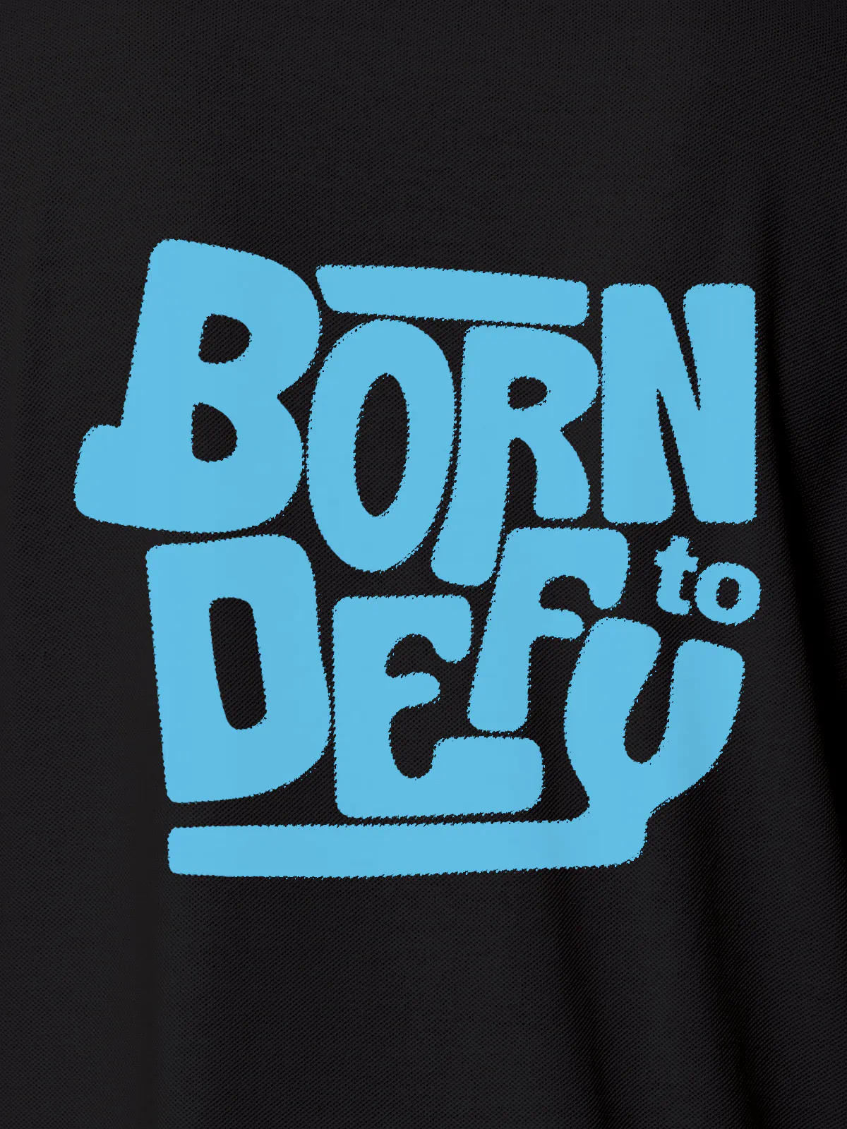 Close up of 'Born To Defy' design on Women's Dark Grey Polo T-shirt, highlighting intricate details and vibrant print.