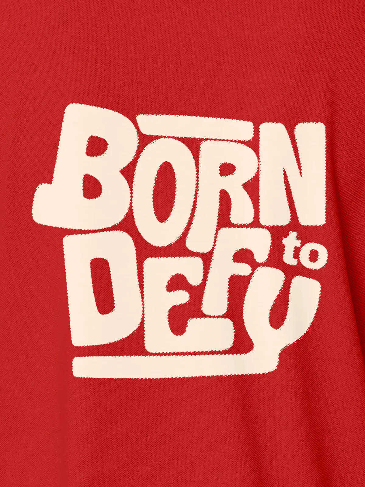 Close up of 'Born To Defy' design on Women's Red Polo T-shirt, highlighting intricate details and vibrant print.