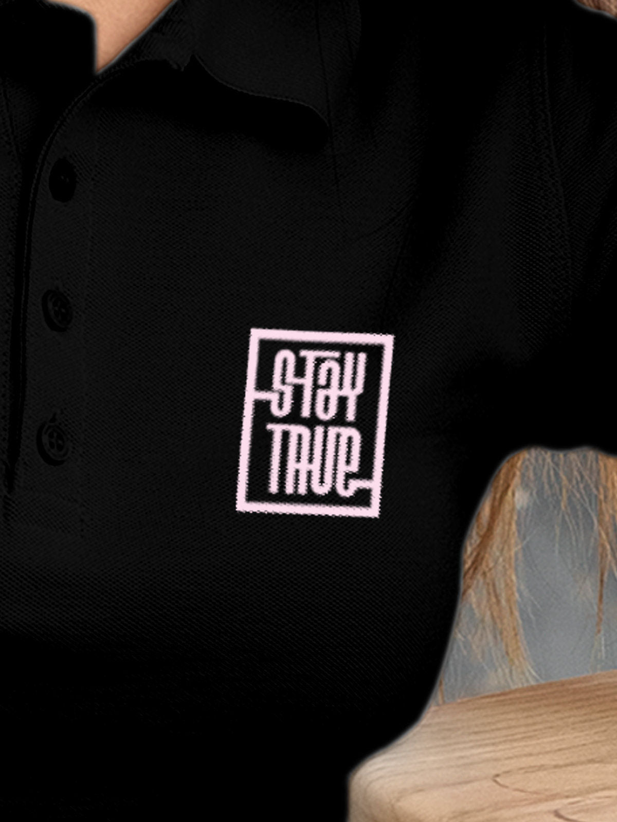 Close up of 'Stay True' design on Women's Black Polo T-shirt, highlighting intricate details and vibrant print.
