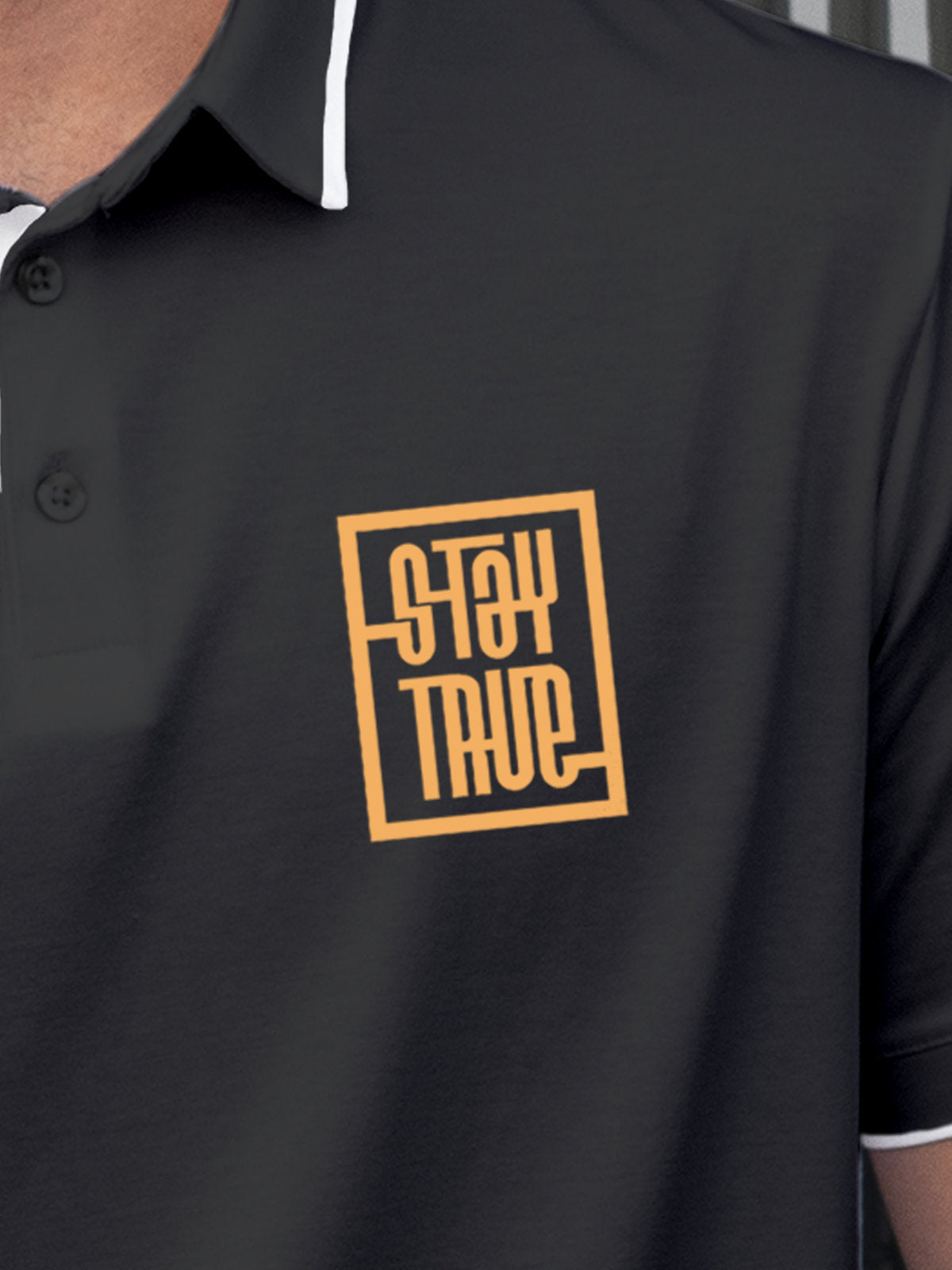 Close up of 'Stay True' on Men's Dark Grey Polo T-shirt, highlighting intricate details and vibrant print.