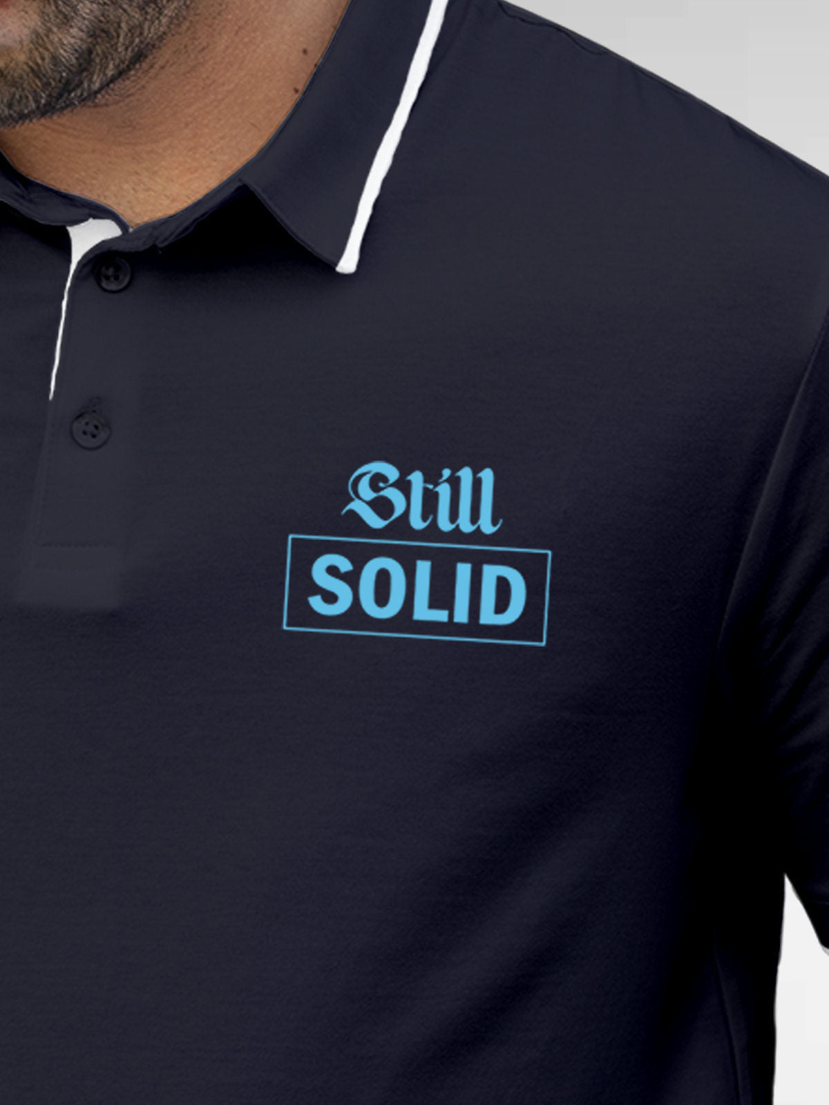 Close up of 'Still Solid' design on Men's Navy Blue Polo T-shirt, highlighting intricate details and vibrant print.