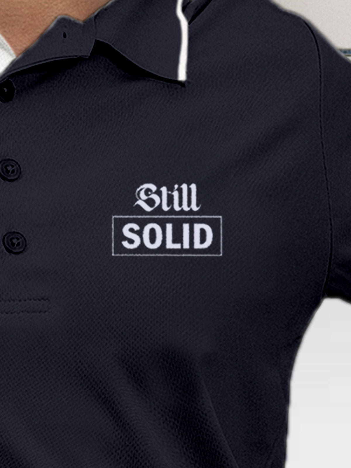 Close up of 'Still Solid' design on Women's Navy Blue Polo T-shirt, highlighting intricate details and vibrant print.
