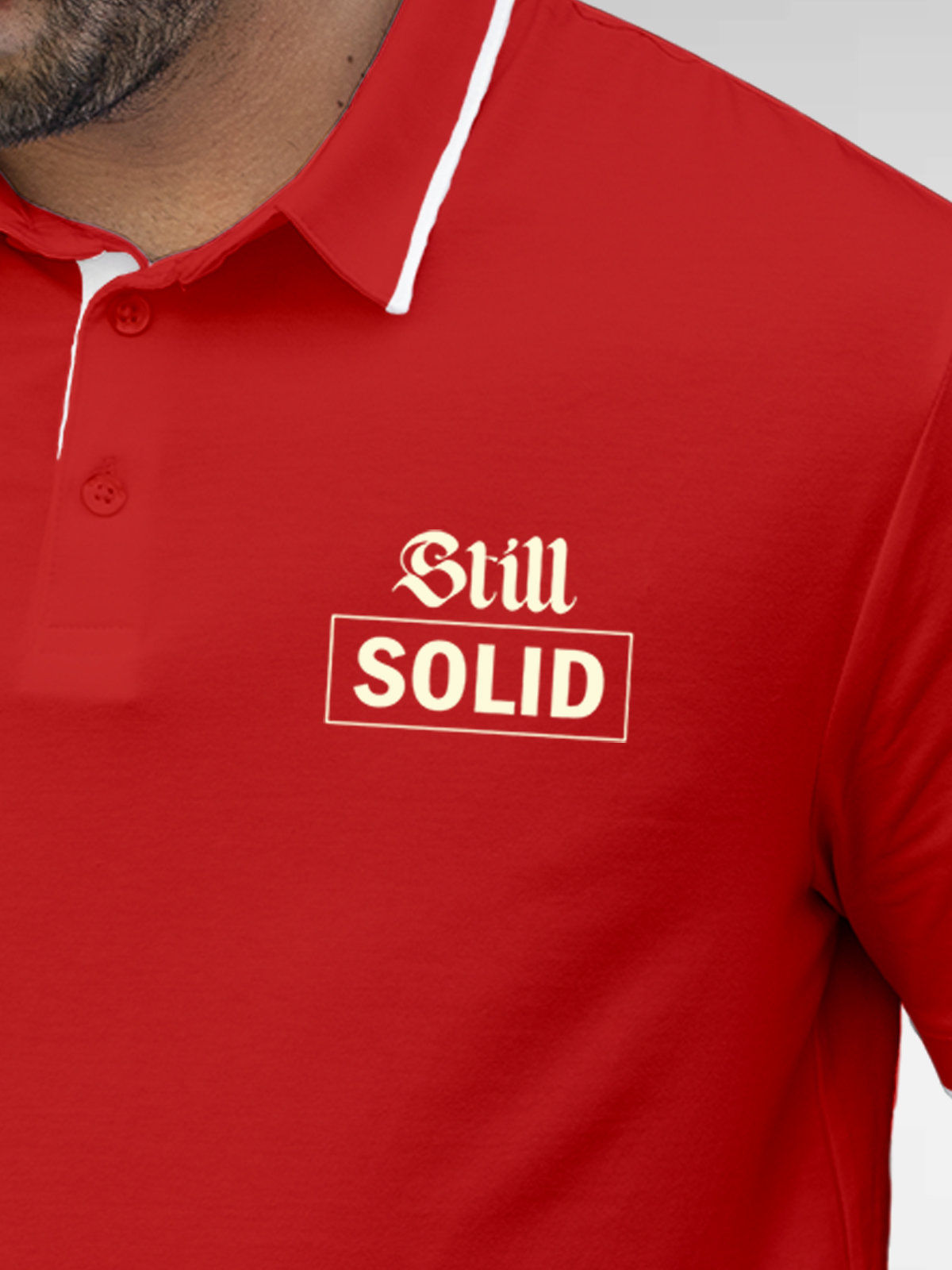 Close up of 'Still Solid' design on Men's Red Polo T-shirt, highlighting intricate details and vibrant print.