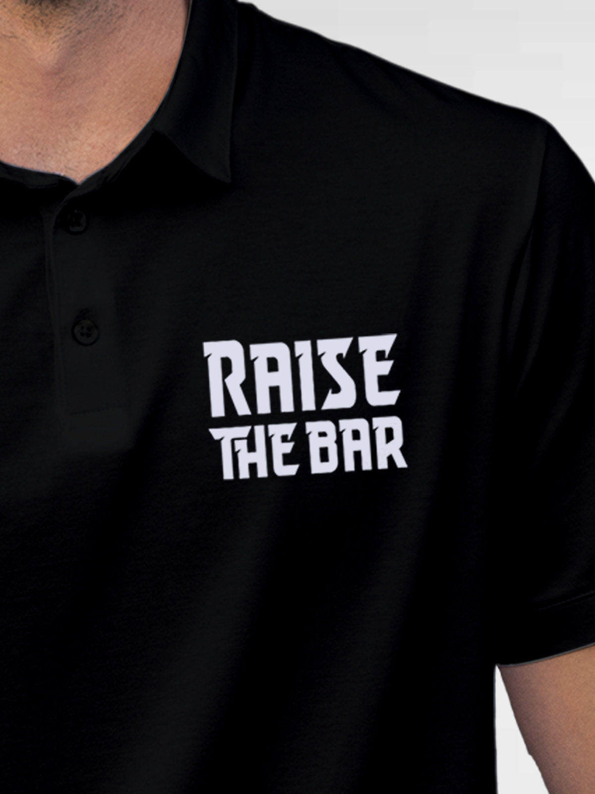 Close up of 'Raise The Bar' design on Men's Black Polo T-shirt, highlighting intricate details and vibrant print.