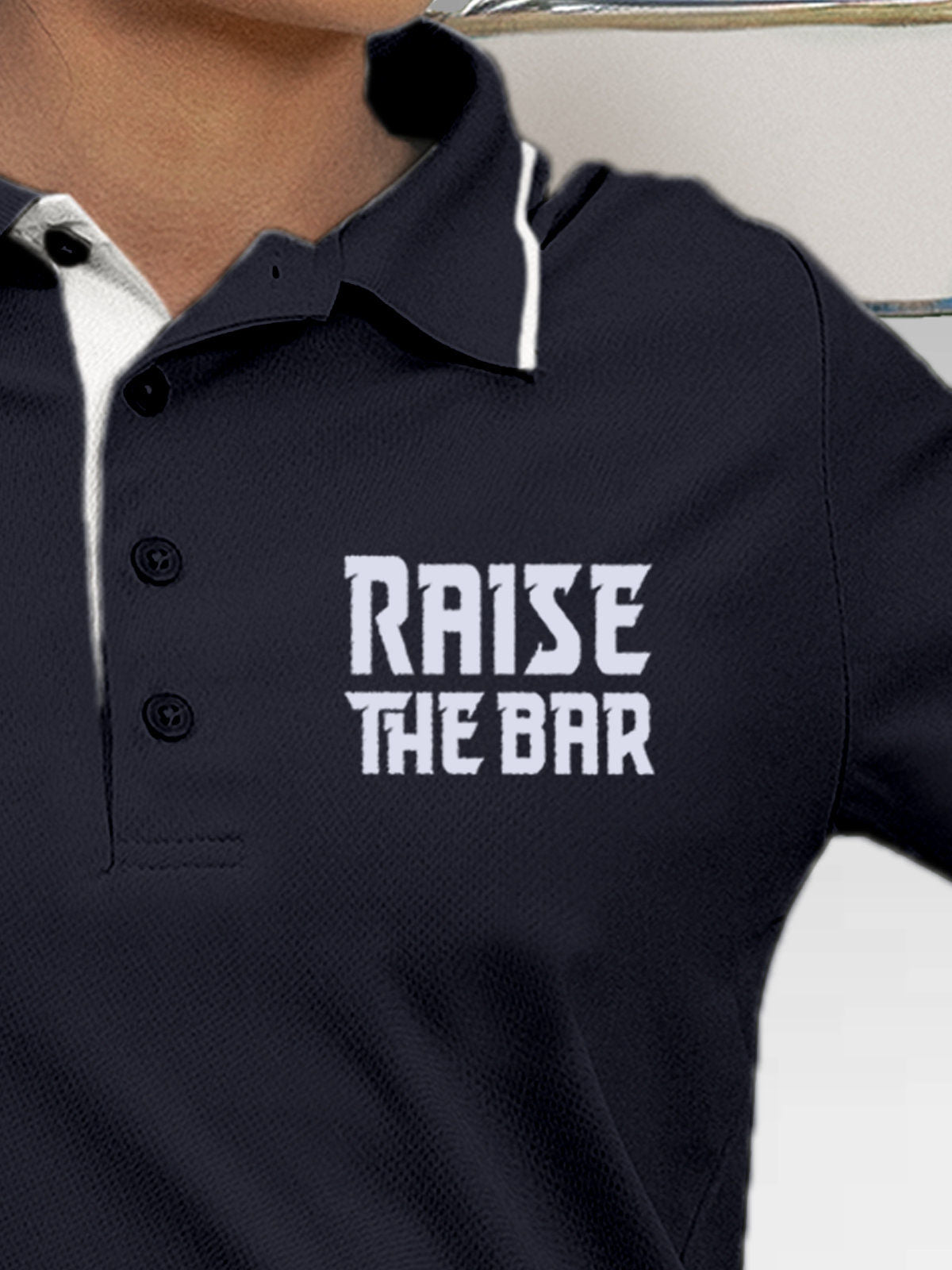 Close up of 'Raise The Bar' design on Women's Navy Blue Polo T-shirt, highlighting intricate details and vibrant print.