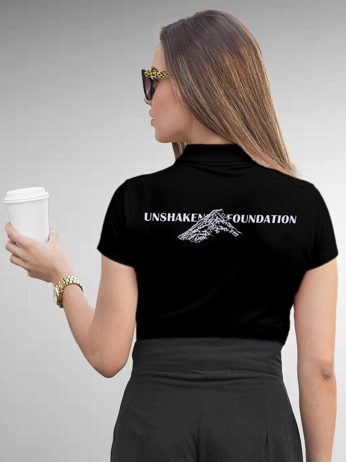 Model wearing Women's Black Polo T-shirt with 'Unshaken Foundation' design, offering effortless style and premium comfort