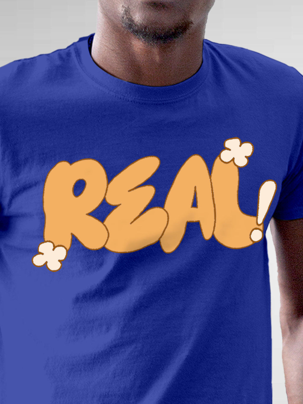 Close up of 'Real' design on Men's Blue Round Neck T-shirt, highlighting intricate details and vibrant print.