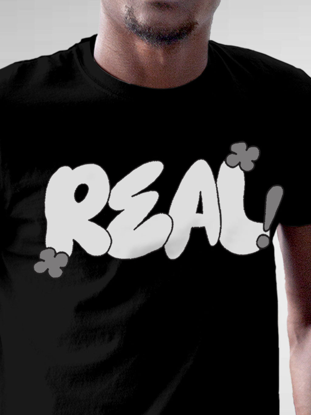 Close up of 'Real' design on Men's Black Round Neck T-shirt, highlighting intricate details and vibrant print.