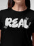 Close up of 'Real' design on Women's Black Round Neck T-shirt, highlighting intricate details and vibrant print.