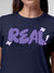 Close up of 'Real' design on Women's Navy Blue Round Neck T-shirt, highlighting intricate details and vibrant print.