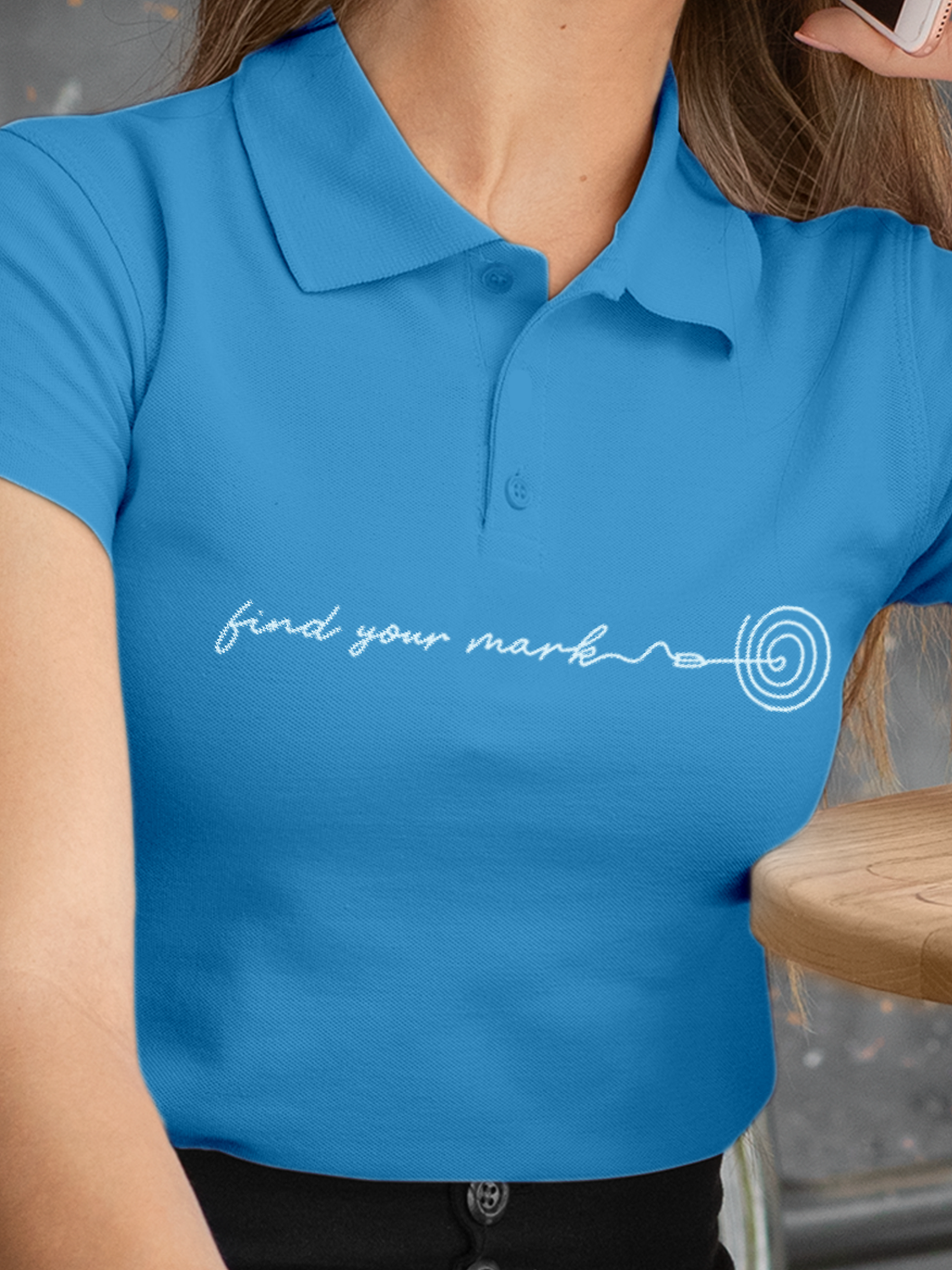 Close up of 'Find Your Mark' design on Women's Blue Polo T-shirt, highlighting intricate details and vibrant print.