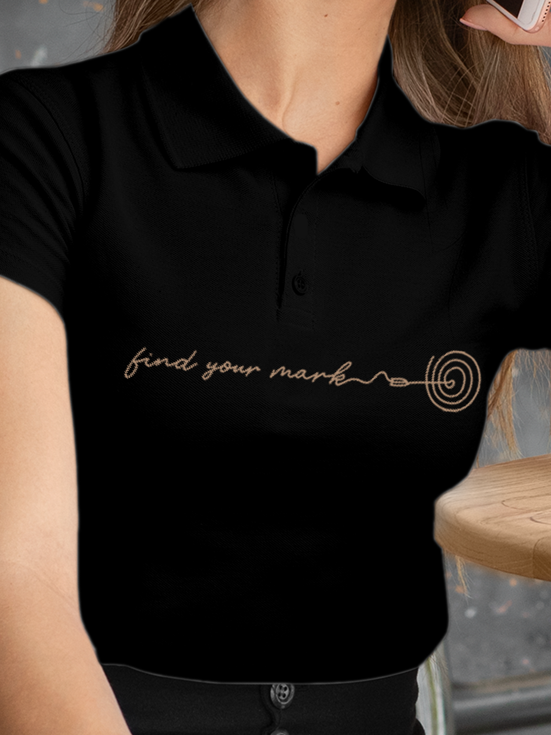 Close up of 'Find Your Mark' design on Women's Black Polo T-shirt, highlighting intricate details and vibrant print.