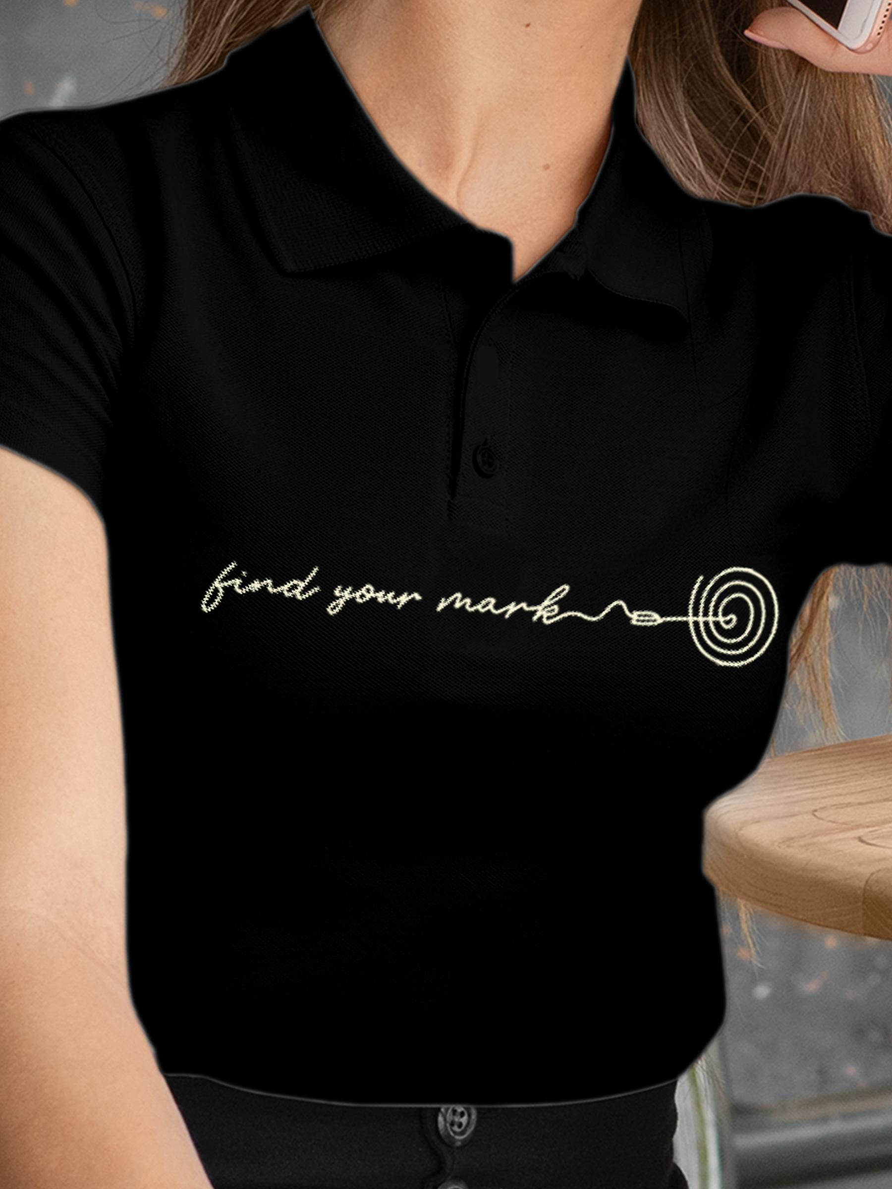 Close up of 'Find Your Mark' design on Women's Black Polo T-shirt, highlighting intricate details and vibrant print.