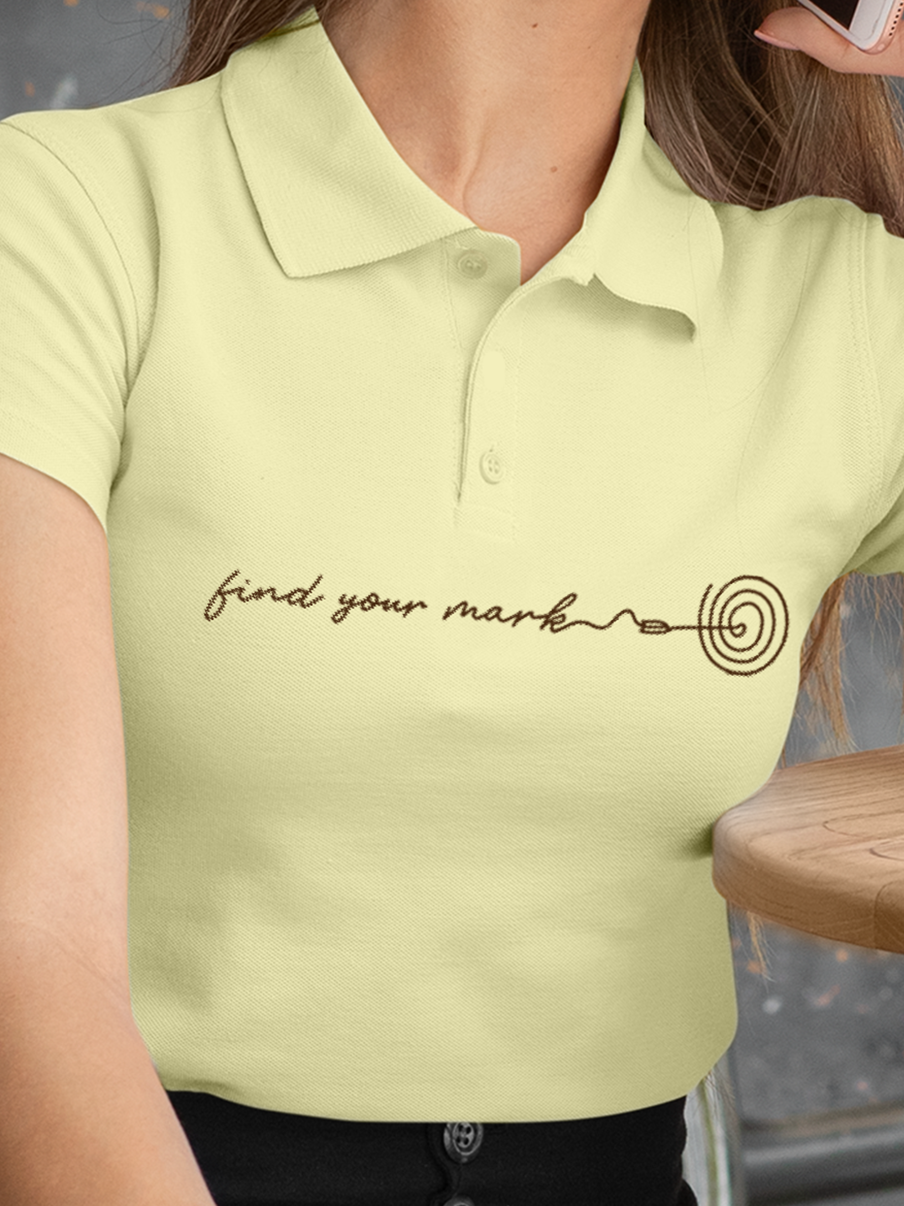 Close up of 'Find Your Mark' design on Women's Yellow Polo T-shirt, highlighting intricate details and vibrant print.