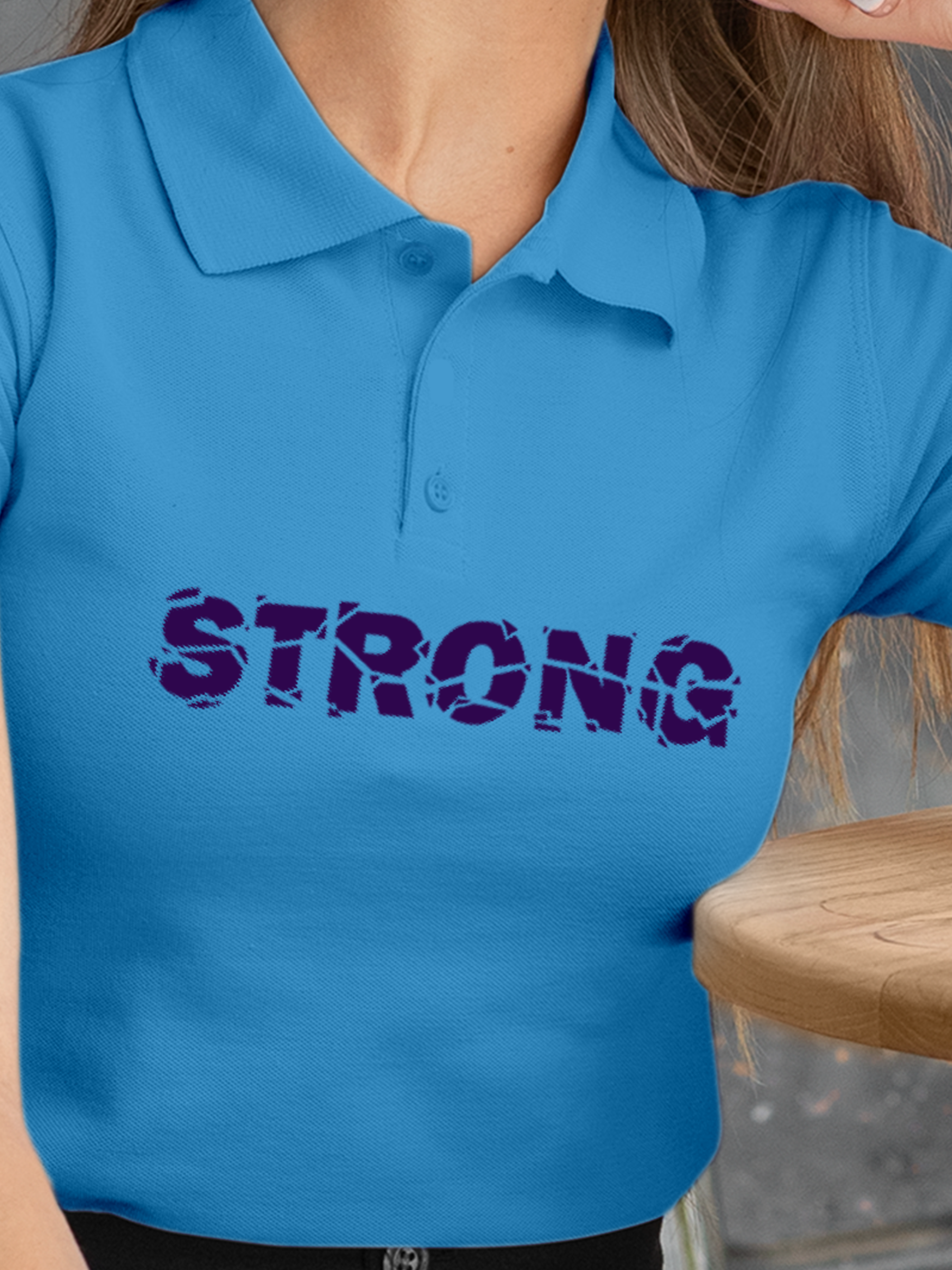 Close up of 'Strong' design on Women's Blue Polo T-shirt, highlighting intricate details and vibrant print.