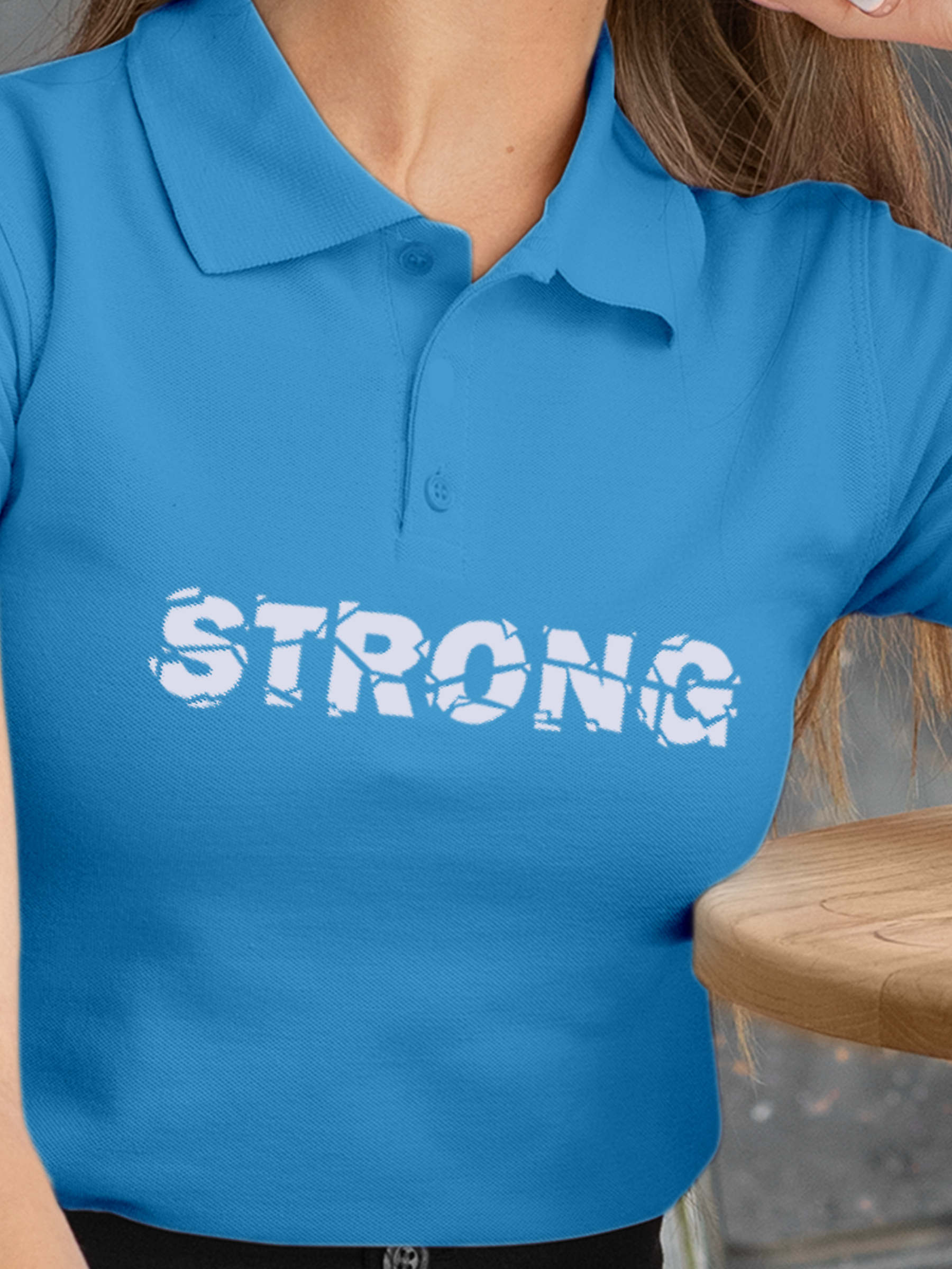 Close up of 'Strong' design on Women's Blue Polo T-shirt, highlighting intricate details and vibrant print.