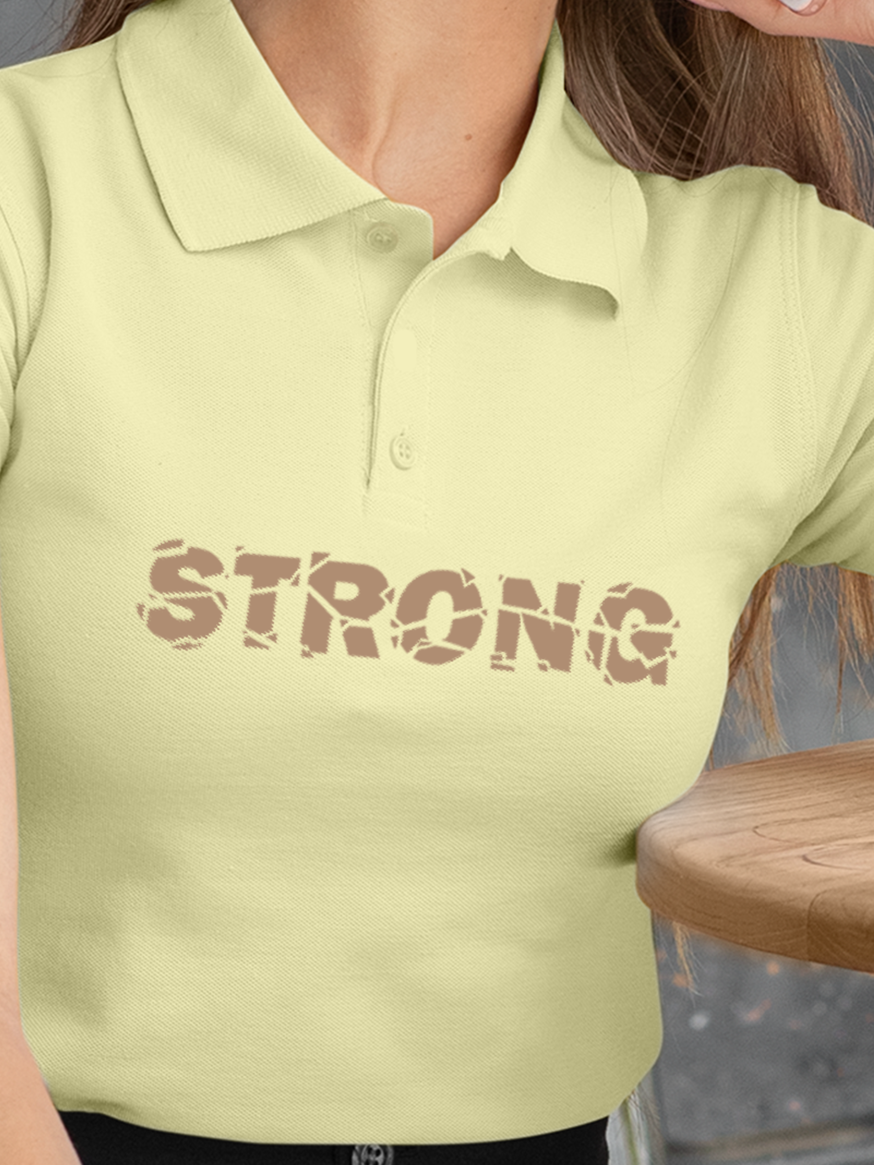 Close up of 'Strong' design on Women's Yellow Polo T-shirt, highlighting intricate details and vibrant print.