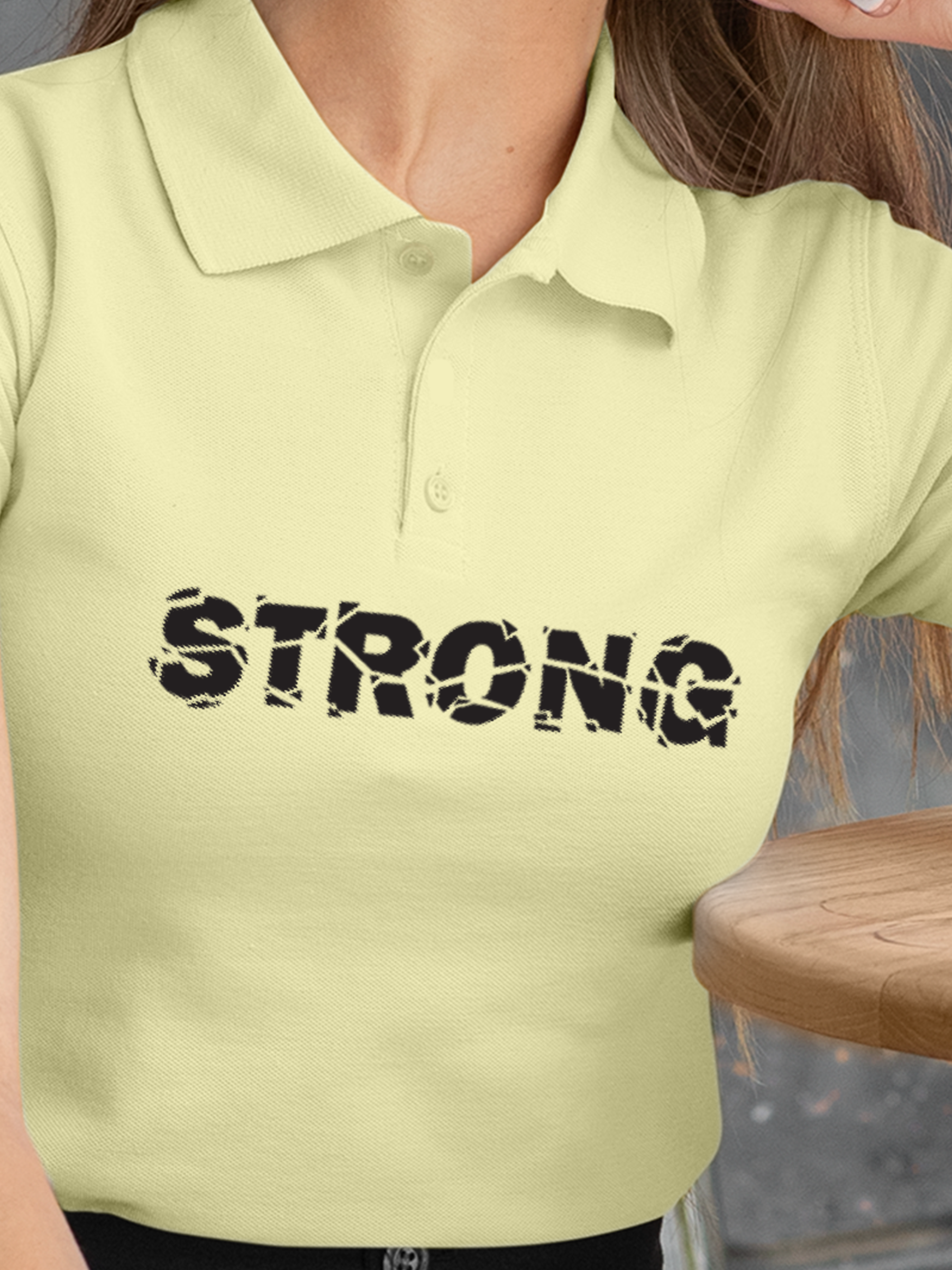 Close up of 'Strong' design on Women's Yellow Polo T-shirt, highlighting intricate details and vibrant print.