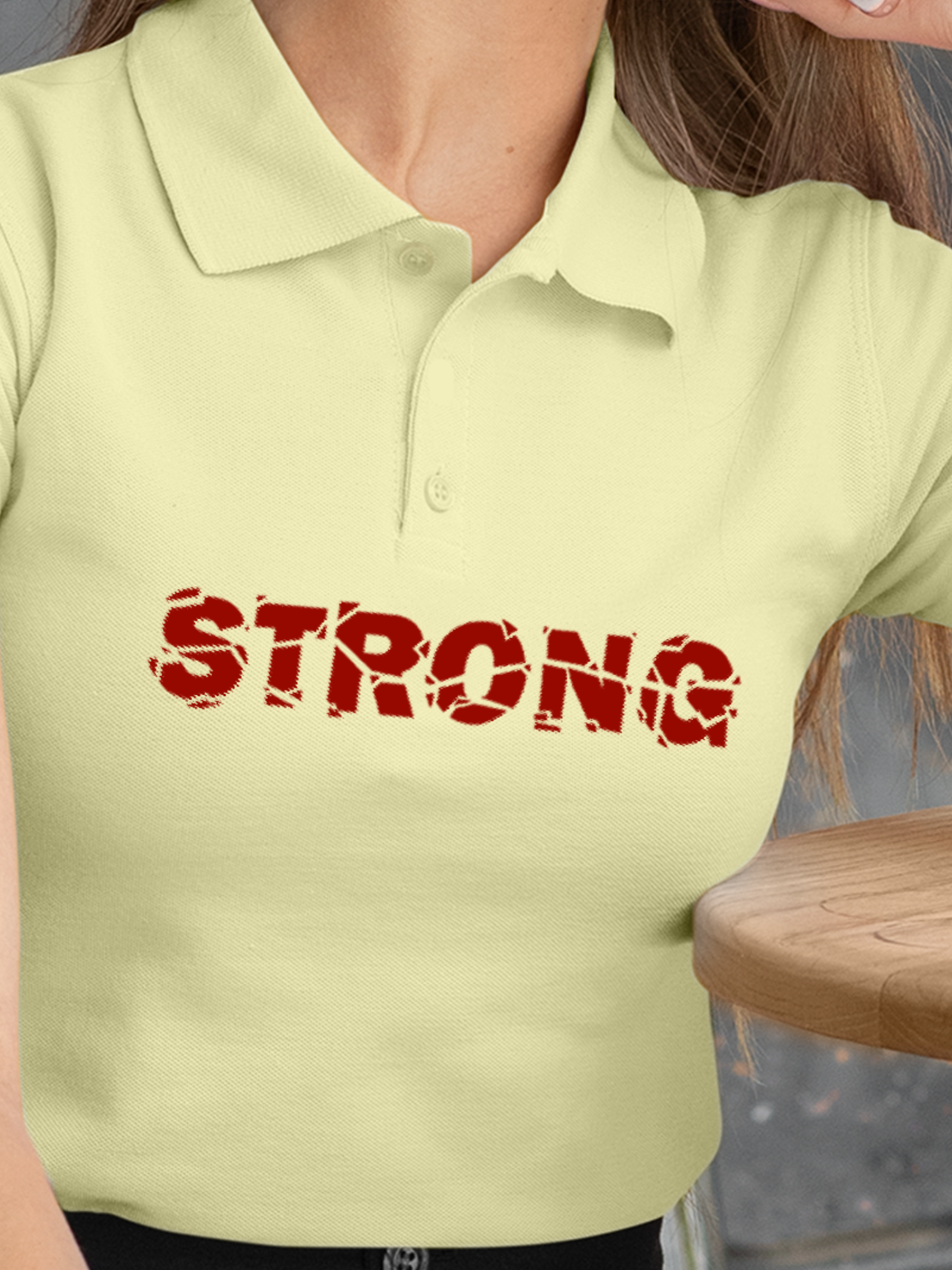 Close up of 'Strong' design on Women's Yellow Polo T-shirt, highlighting intricate details and vibrant print.
