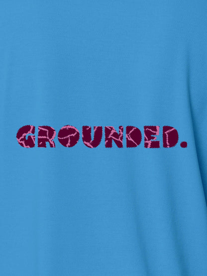 Close up of 'Grounded' design on Women's Blue Polo T-shirt, highlighting intricate details and vibrant print.