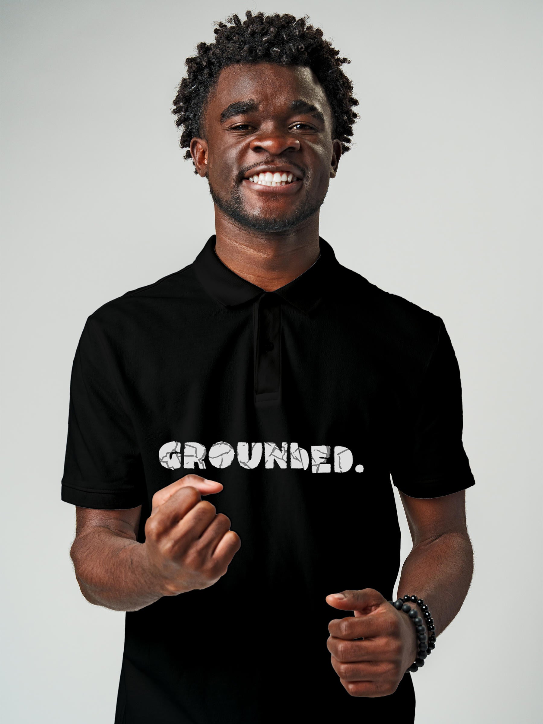 Model wearing Men's Black Polo T-shirt with 'Grounded' design, offering effortless style and premium comfort