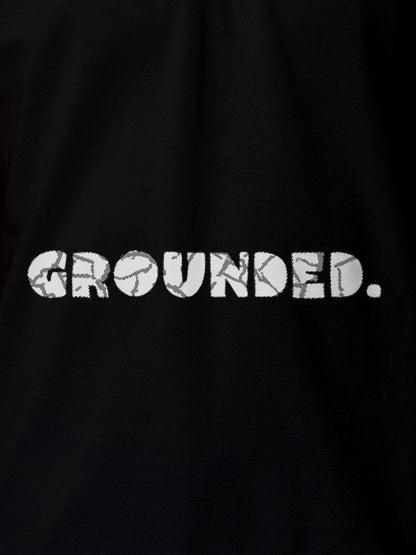 Close up of 'Grounded' design on Men's Black Polo T-shirt, highlighting intricate details and vibrant print.