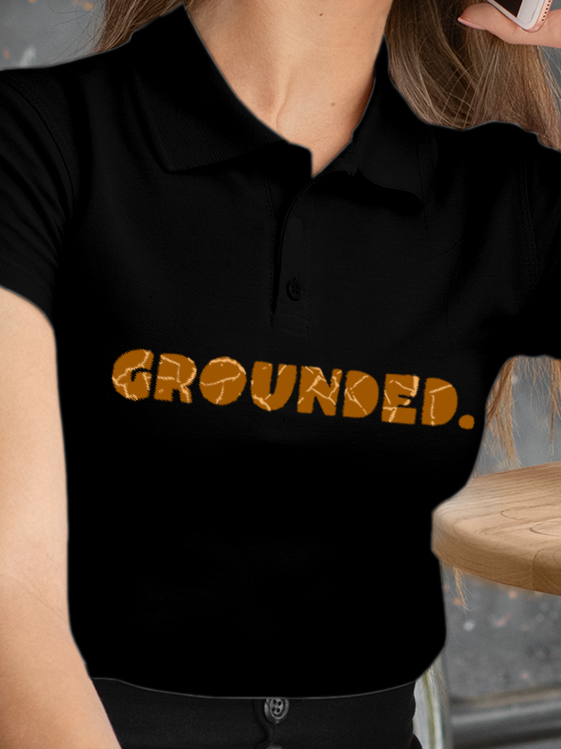 Close up of 'Grounded' design on Women's Black Polo T-shirt, highlighting intricate details and vibrant print.