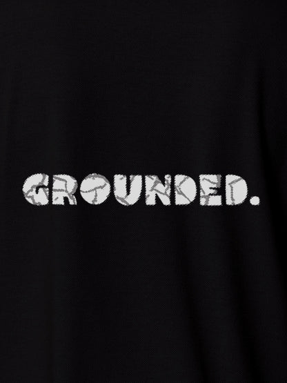 Close up of 'Grounded' design on Women's Black Polo T-shirt, highlighting intricate details and vibrant print.
