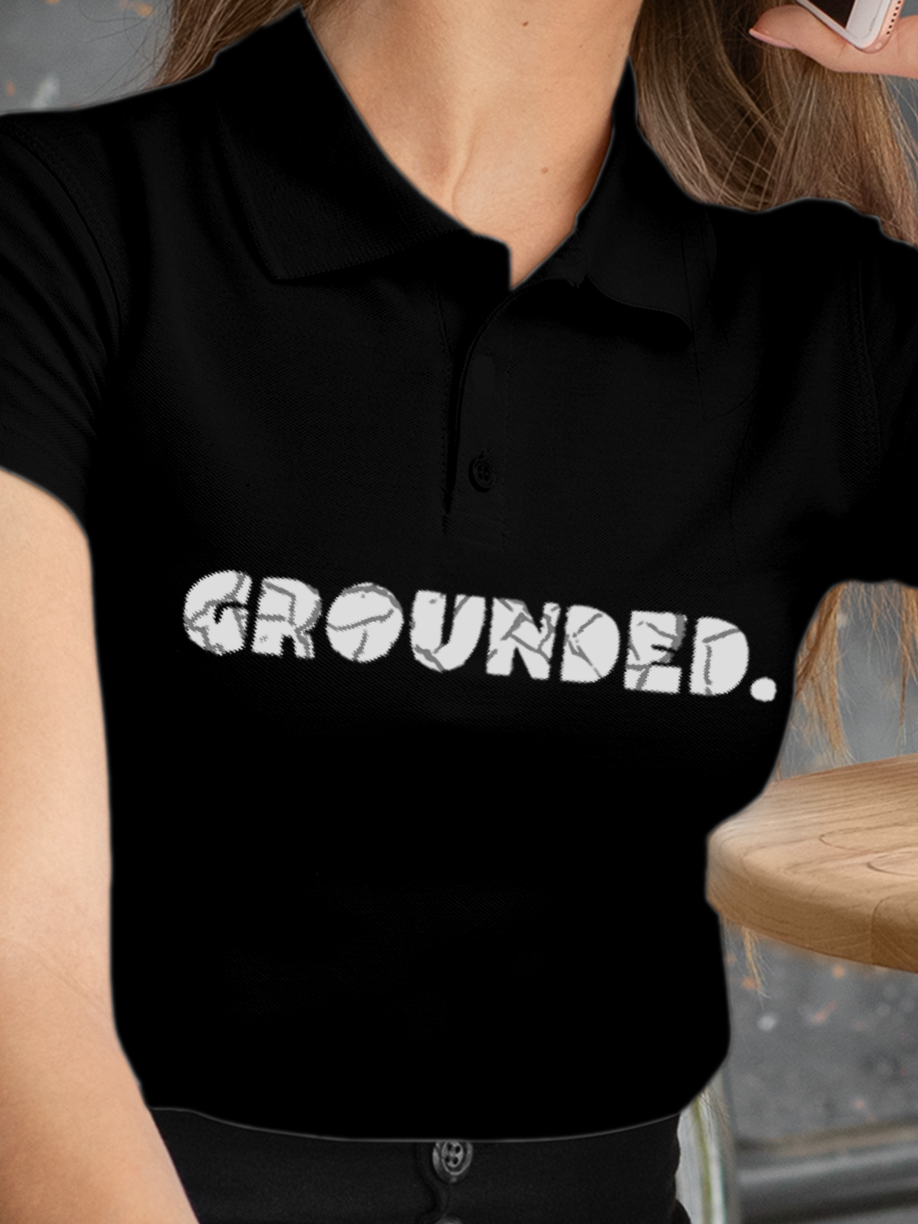 Close up of 'Grounded' design on Women's Black Polo T-shirt, highlighting intricate details and vibrant print.
