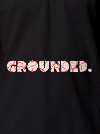 Close up of 'Grounded' design on Men's Dark Grey Polo T-shirt, highlighting intricate details and vibrant print.
