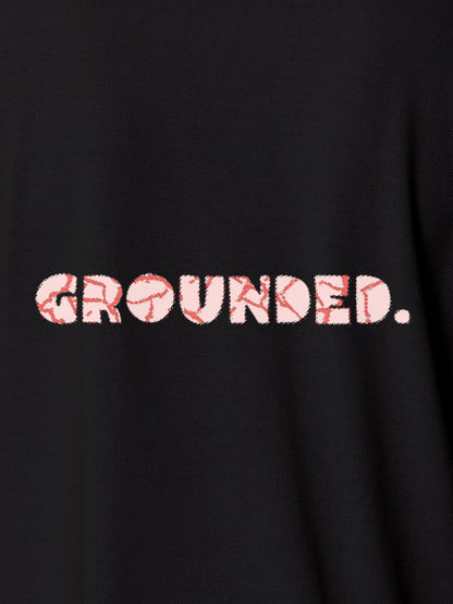 Close up of 'Grounded' design on Women's Dark Grey Polo T-shirt, highlighting intricate details and vibrant print.
