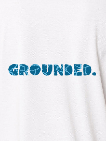 Close up of 'Grounded' design on Women's White Polo T-shirt, highlighting intricate details and vibrant print.
