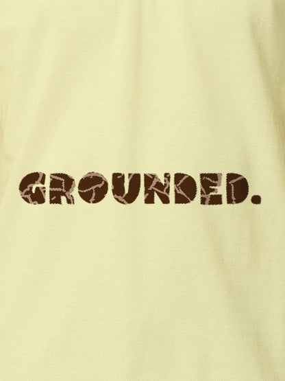 Close up of 'Grounded' design on Men's Yellow Polo T-shirt, highlighting intricate details and vibrant print.