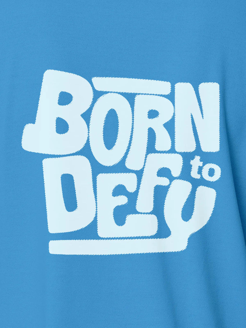 Close up of 'Born To Defy' design on Women's Blue Polo T-shirt, highlighting intricate details and vibrant print.