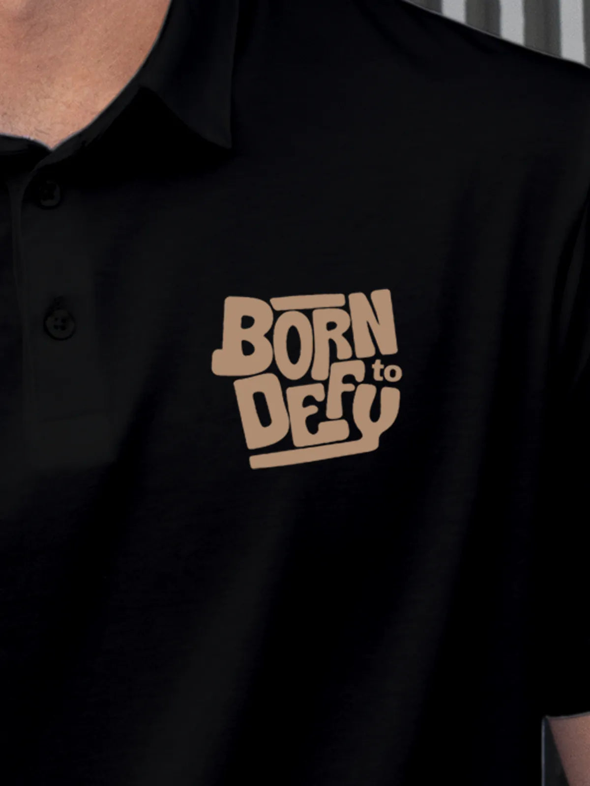 Close up of 'Born To Defy' on Men's Black Polo T-shirt, highlighting intricate details and vibrant print.