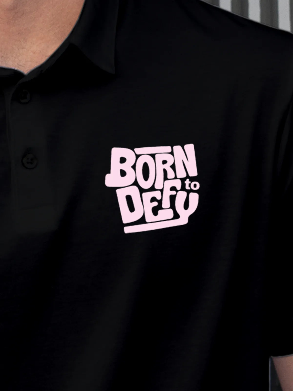 Close up of 'Born To Defy' on Men's Black Polo T-shirt, highlighting intricate details and vibrant print.