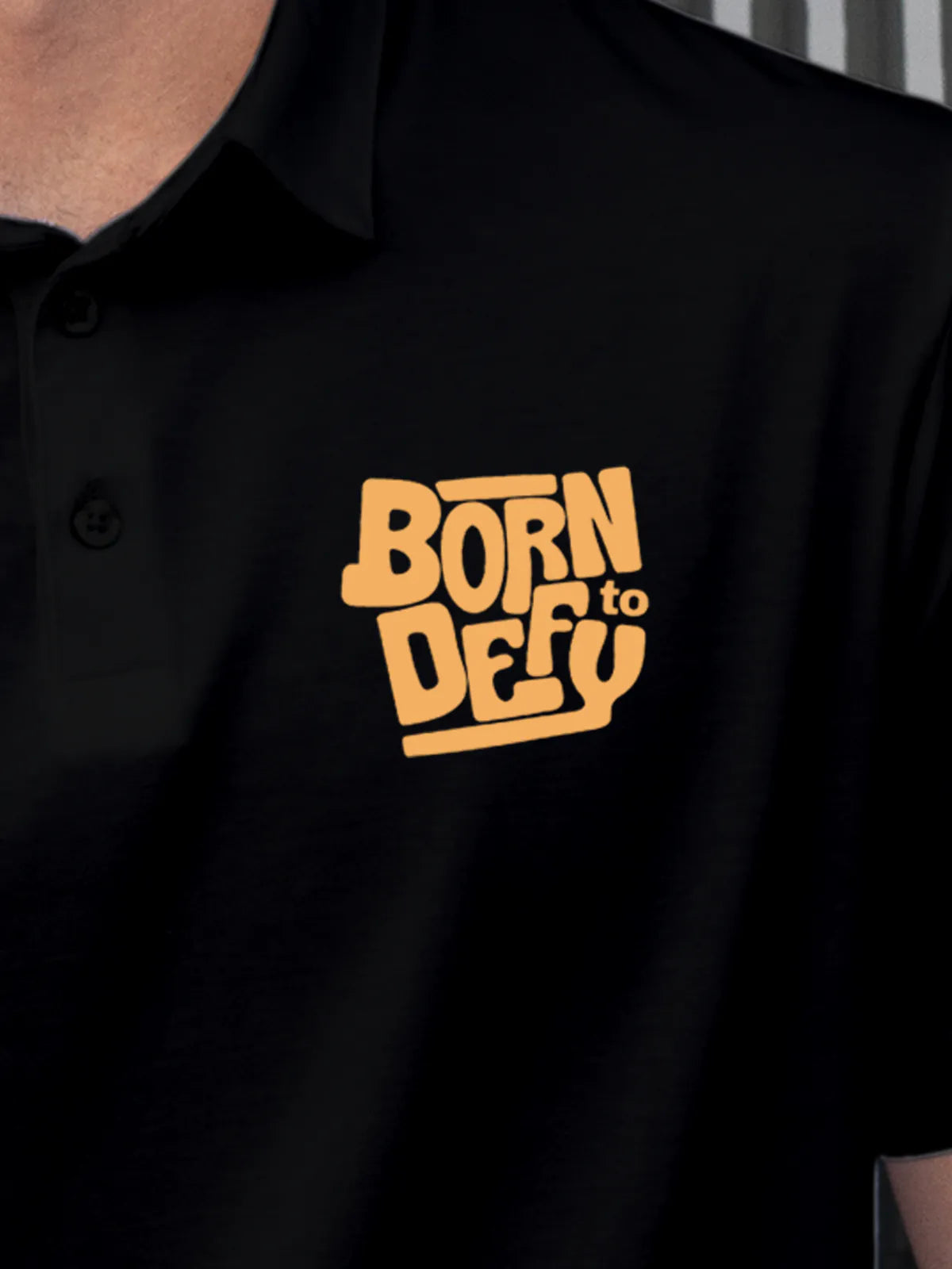 Close up of 'Born To Defy' on Men's Black Polo T-shirt, highlighting intricate details and vibrant print.