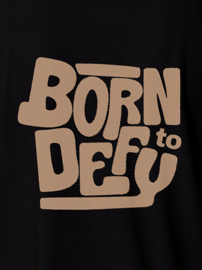 Close up of 'Born To Defy' design on Women's Black Polo T-shirt, highlighting intricate details and vibrant print.